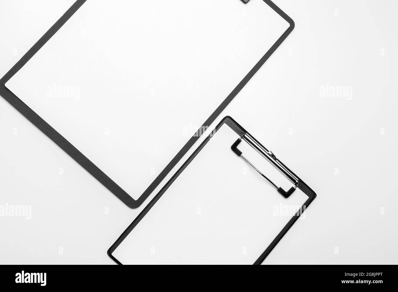 Negli appunti di nero con vuoto foglio bianco attaccato su sfondo bianco Foto Stock