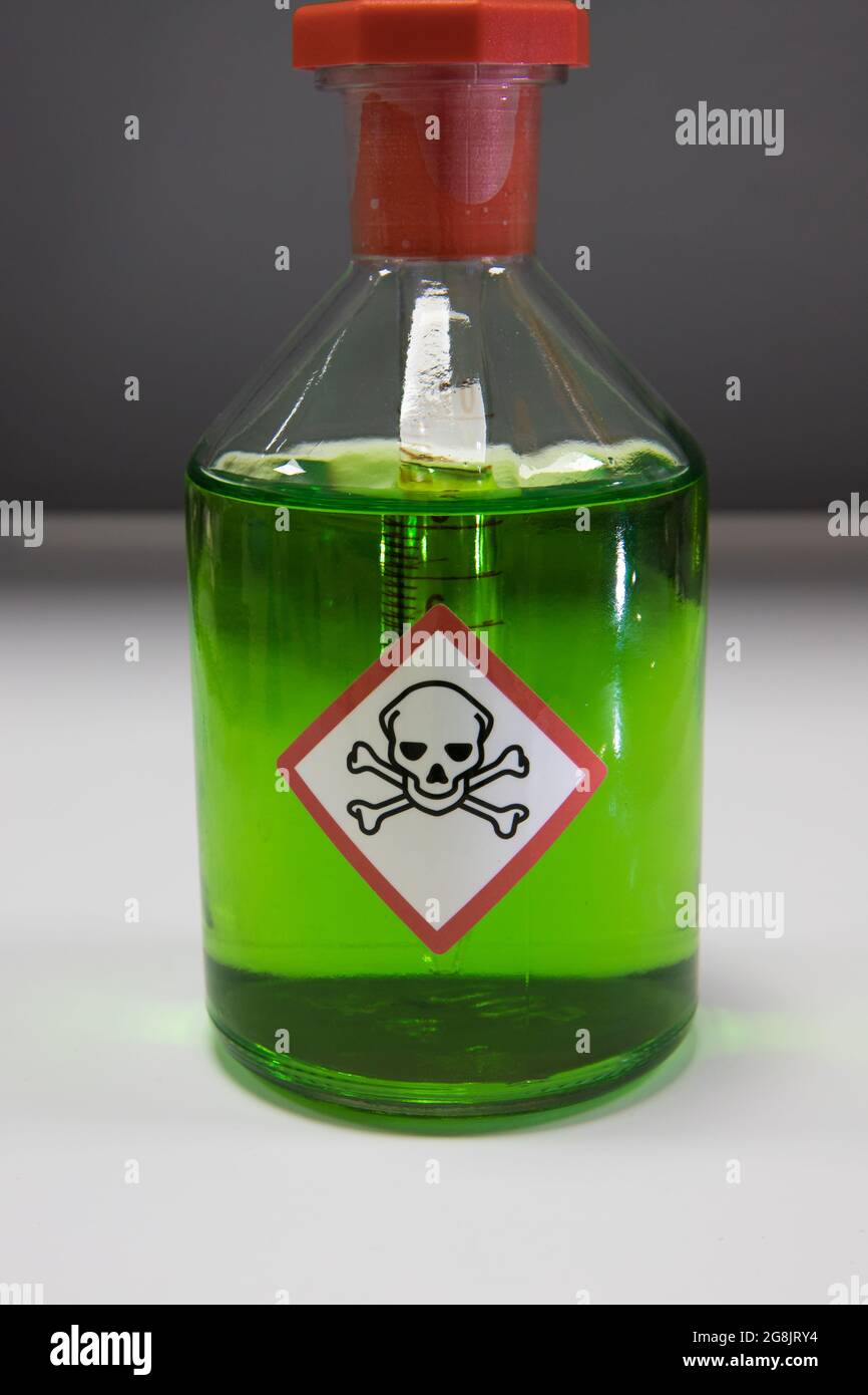 Sostanza chimica ecologica tossica in un laboratorio scientifico. Matraccio di vetro con etichetta di ossatura tossica del cranio e delle ossa incrociate Foto Stock