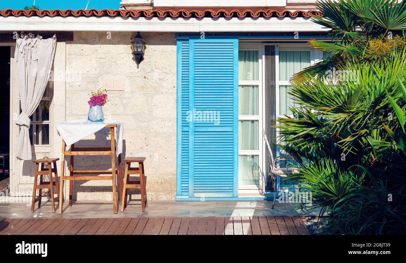 Patio esterno di una tradizionale casa in pietra egea con tavolo e sgabelli decorativi rustici in legno. Foto Stock