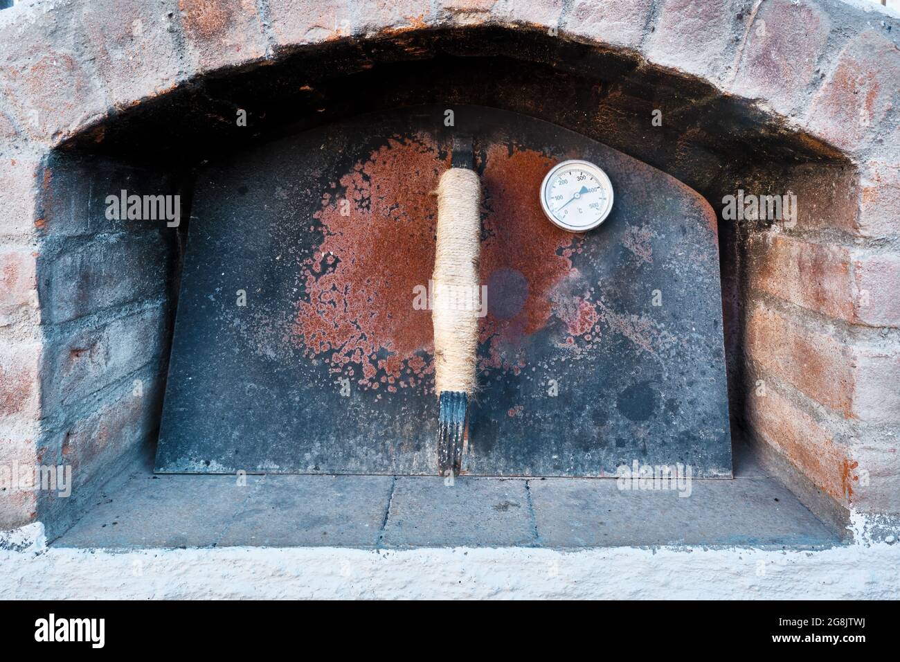 Forno in pietra con porta chiusa in metallo arrugginito e termometro  termico Foto stock - Alamy