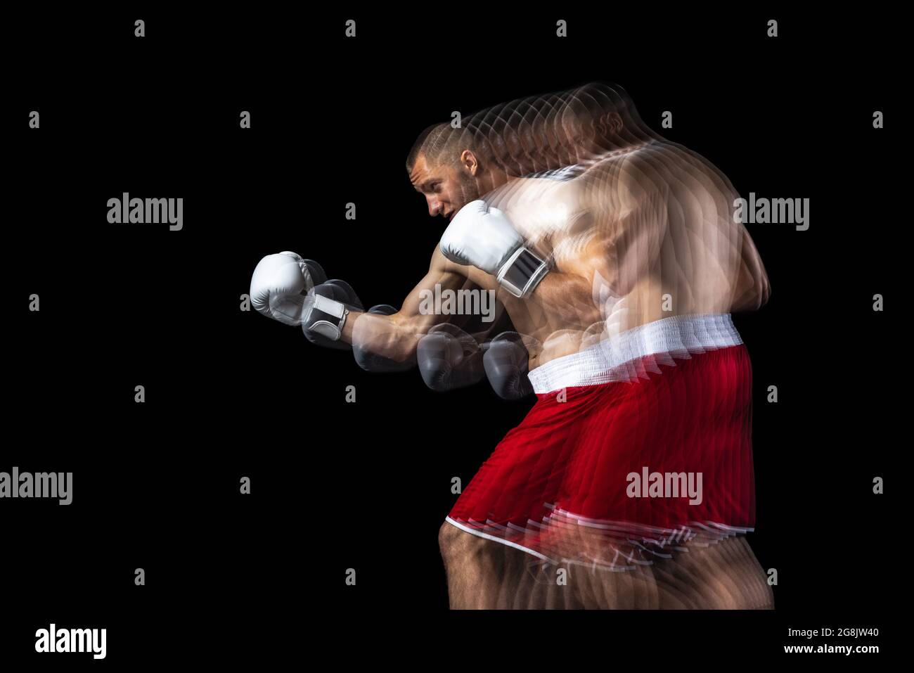 Giovane pugile professionista in formazione shorts rossi, allenandosi su sfondo nero. Effetto stroboscopio Foto Stock