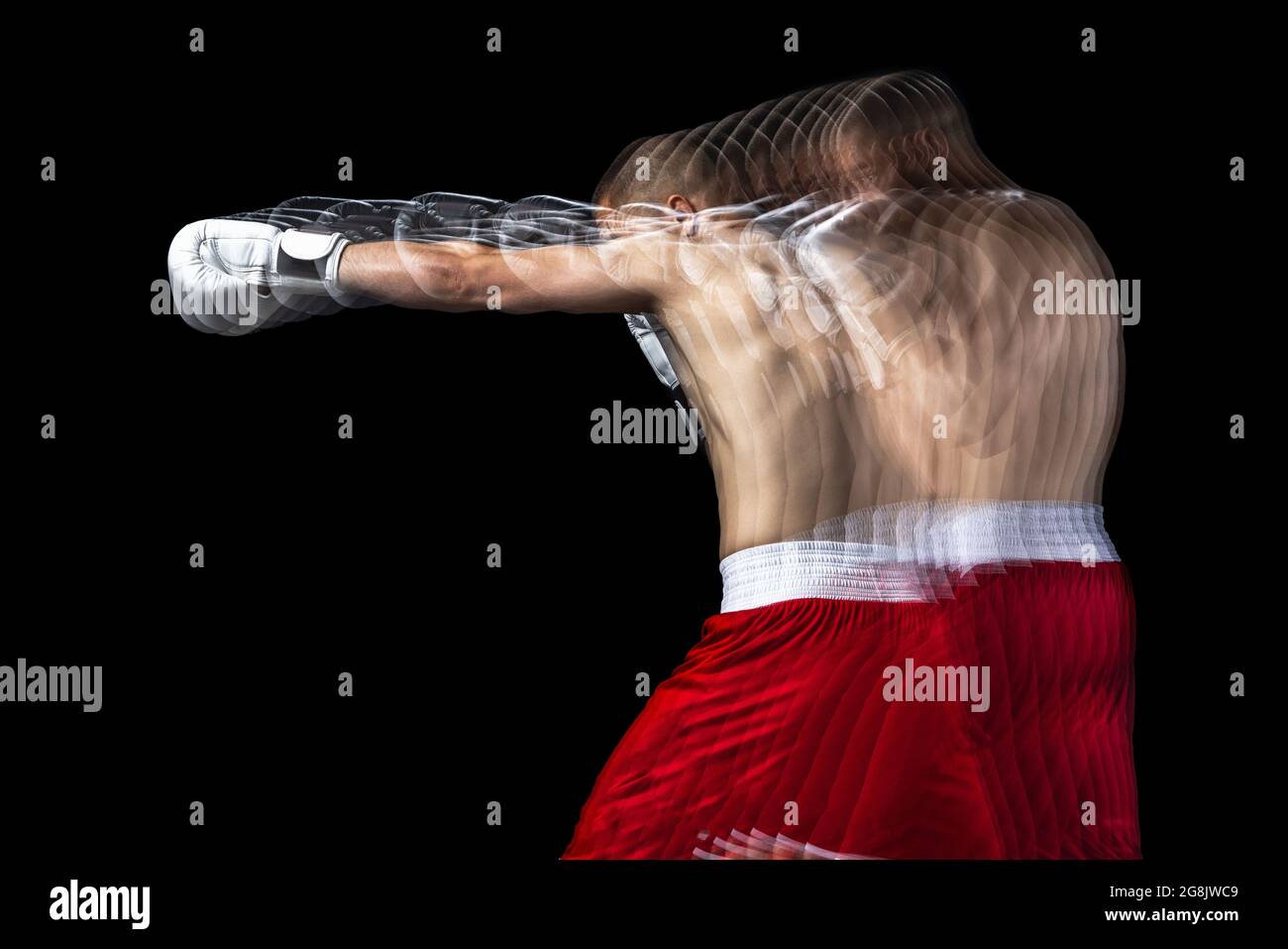 Giovane pugile professionista in shorts rosso allenamento, allenandosi su sfondo nero. Stroboscopio Foto Stock