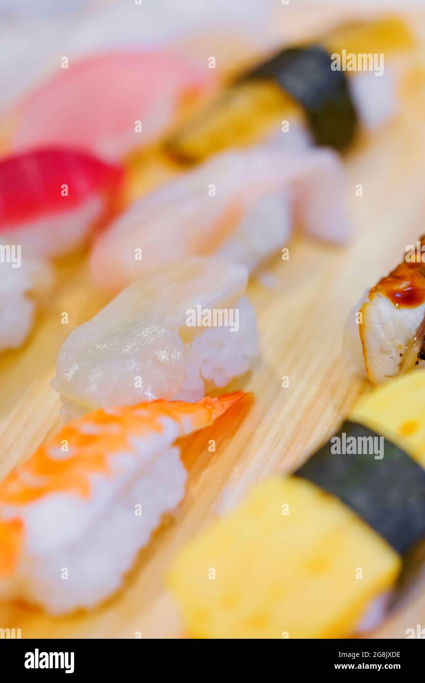 Primo piano su gamberi giapponesi ebi e sushi all'uovo alla griglia tamagoyaki con altri pezzi di pesce di riso nigirizushi pressati a mano, tra cui calamari ika, hotate Foto Stock