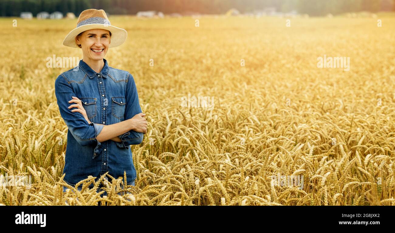 sorridente giovane agricoltore in piedi con le braccia incrociate in campo di cereali di grano. copia spazio Foto Stock