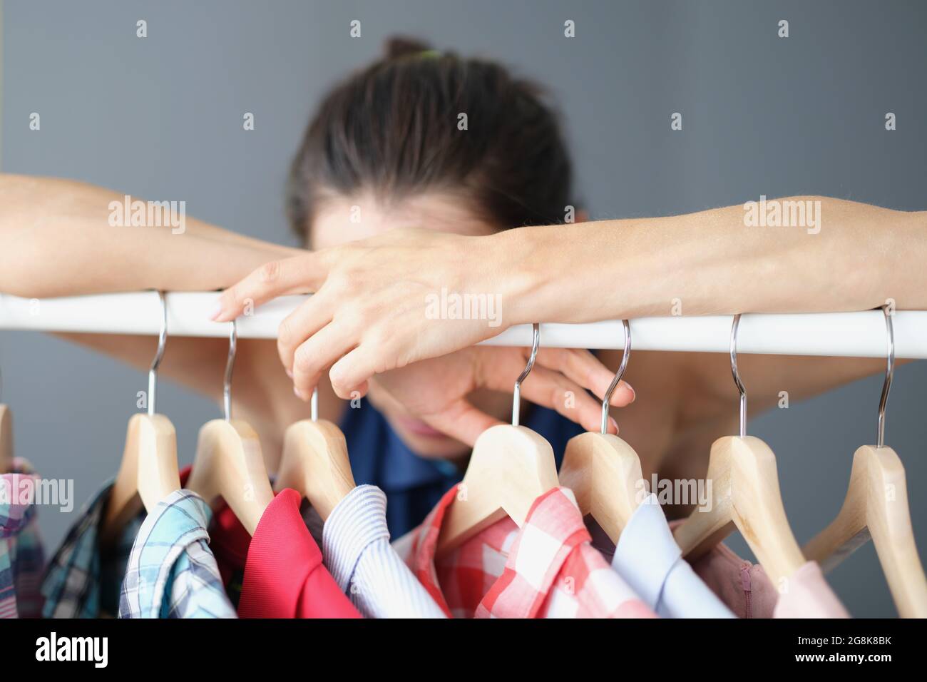 La donna frustrata non può scegliere i vestiti nel guardaroba Foto Stock