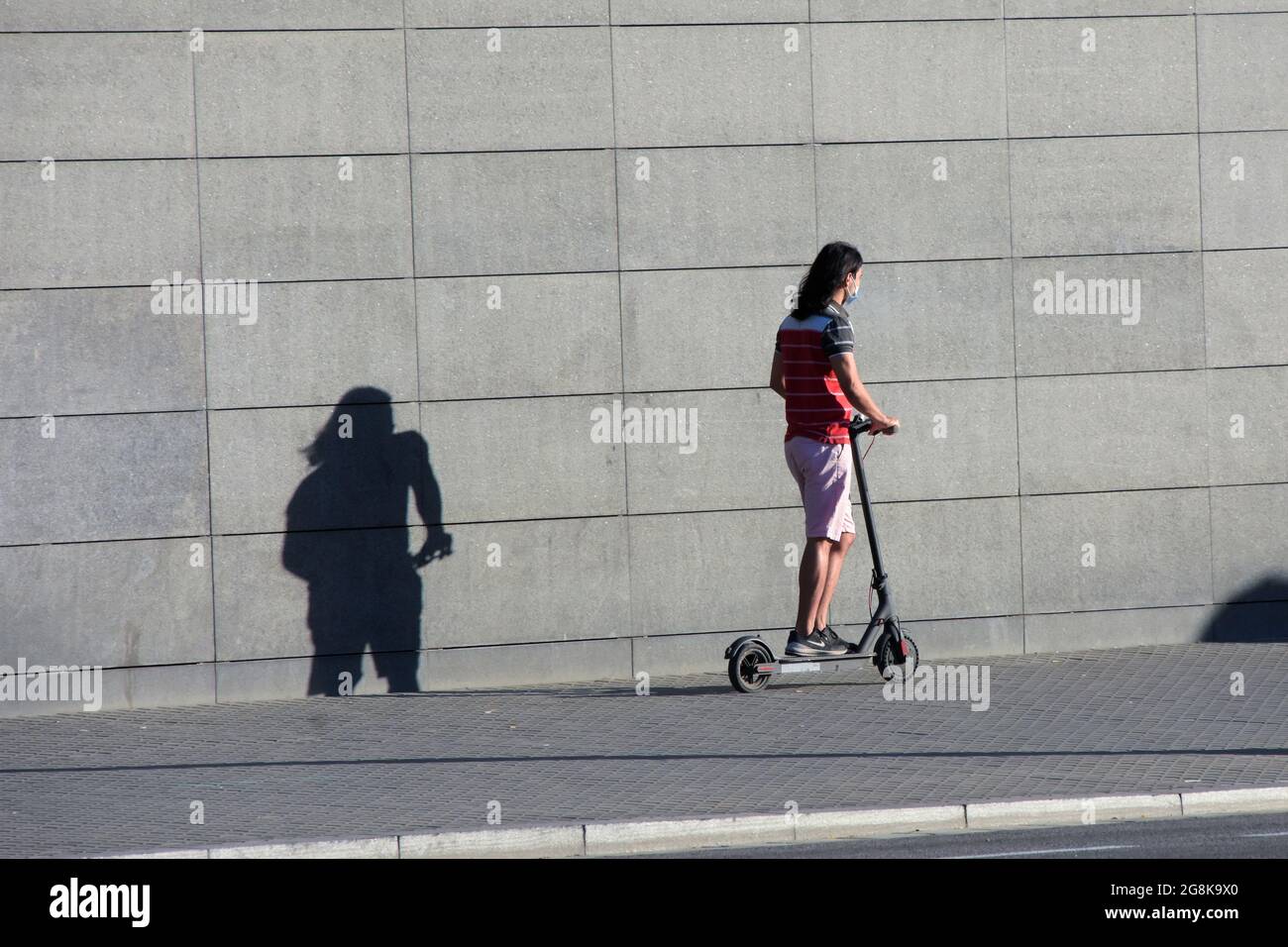 Il giovane guida uno scooter elettrico in una strada di una città. Foto Stock