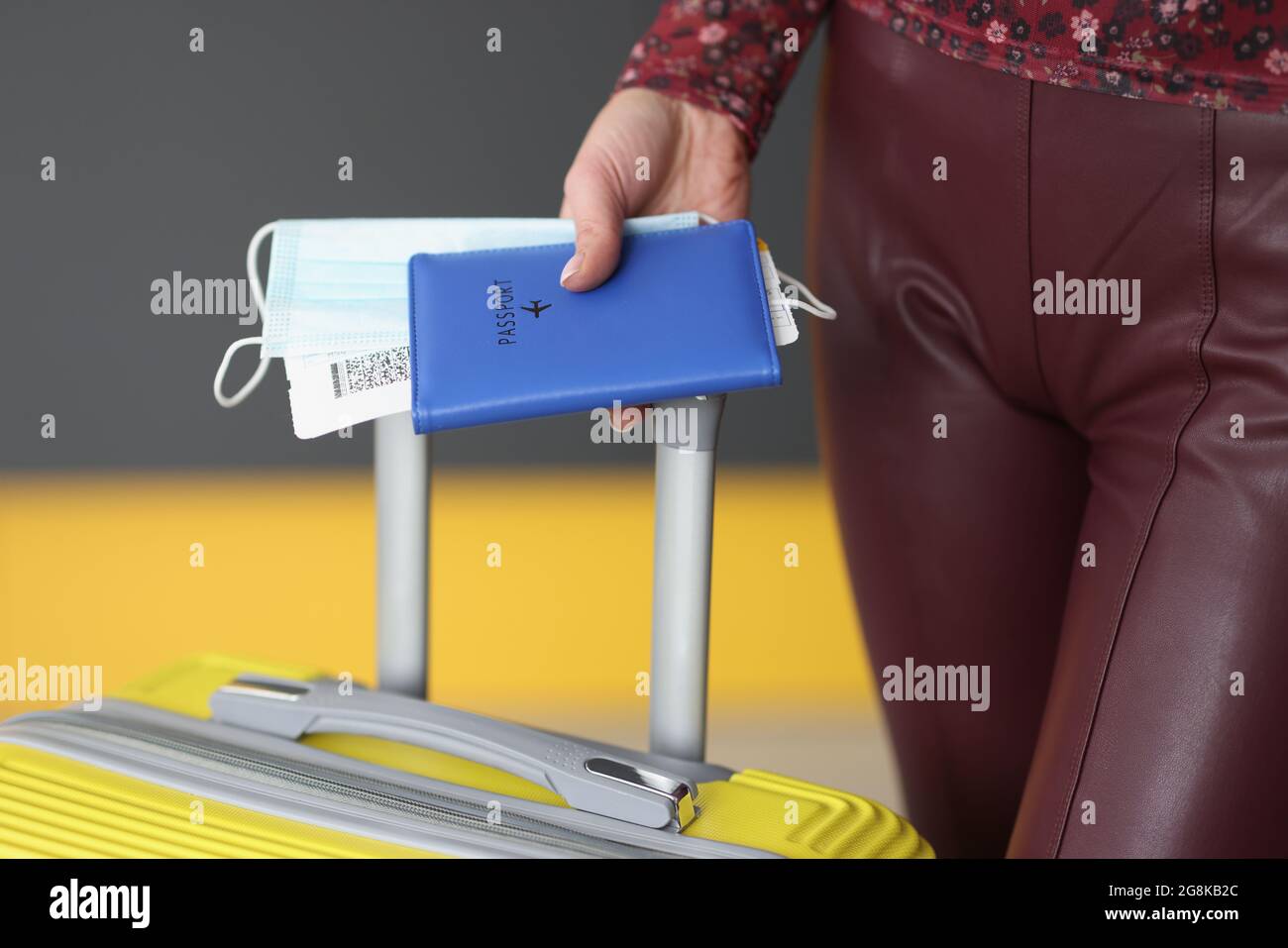Donna con passaporto, biglietto aereo, maschera medica e valigia Foto Stock