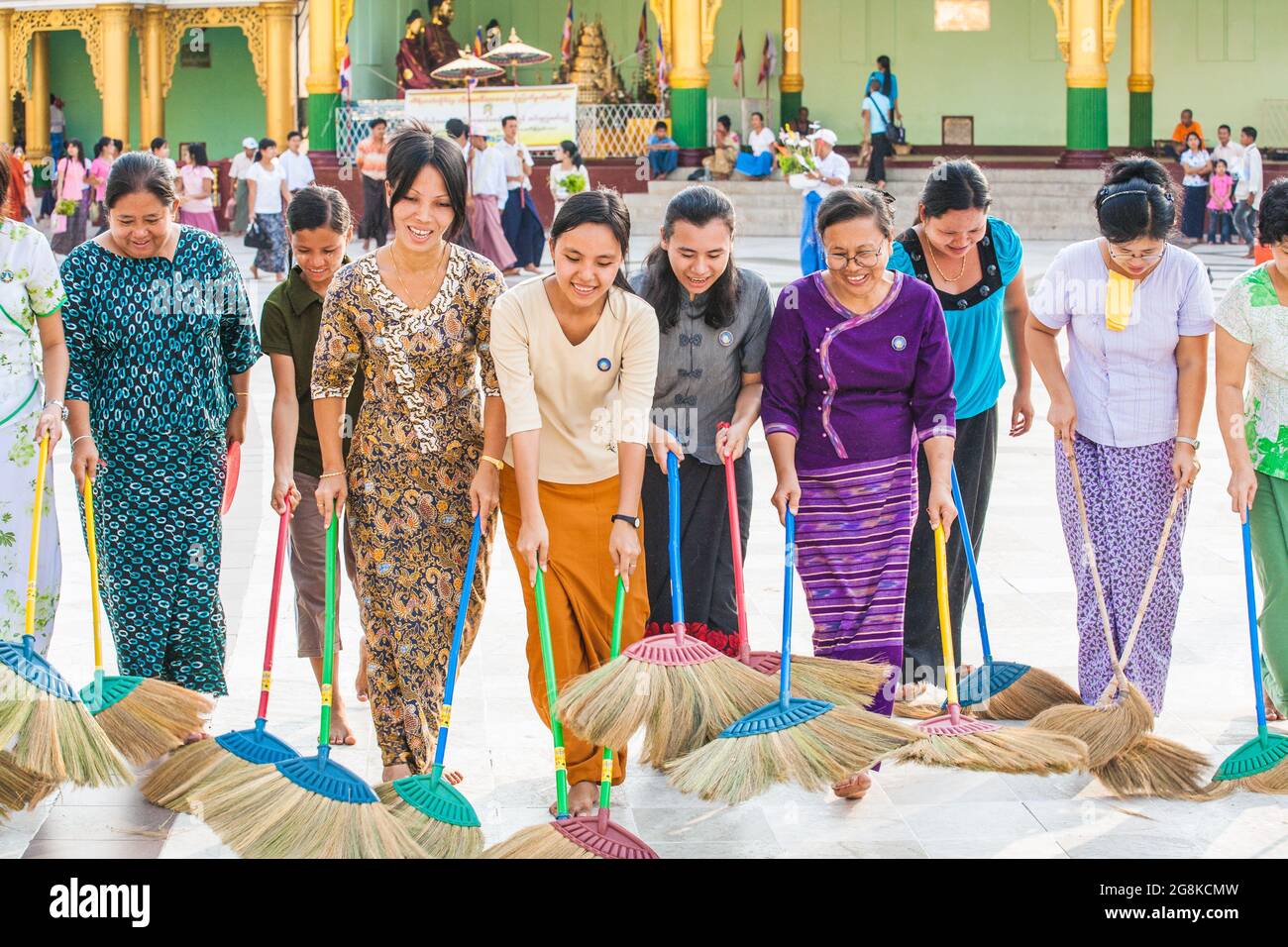 Fila di Signore birmani che spazzano pavimento in marmo all'unisono con scopa a Shwedagon Pagoda per guadagnare merito o credito spirituale, Yangon, Myanmar Foto Stock