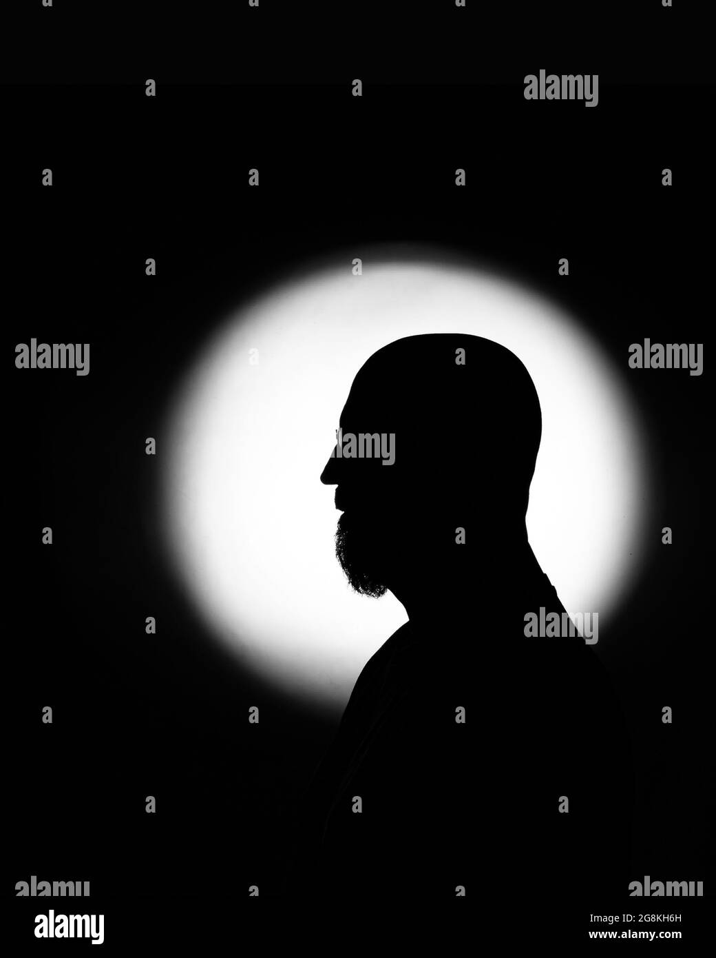 Ombra di un uomo riflessa su una luce rotonda bianca isolata su uno sfondo scuro Foto Stock