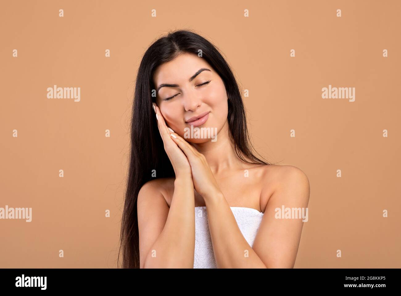 Concetto di sollevamento del viso. Donna armena felice con gli occhi chiusi  che toccano la pelle morbida sulle guance su sfondo beige Foto stock - Alamy