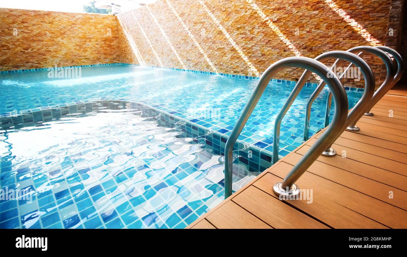 Una piscina vuota color turchese con barre di appoggio a scala all'alba. Concentrarsi sulla scaletta delle barre di appoggio. Foto Stock