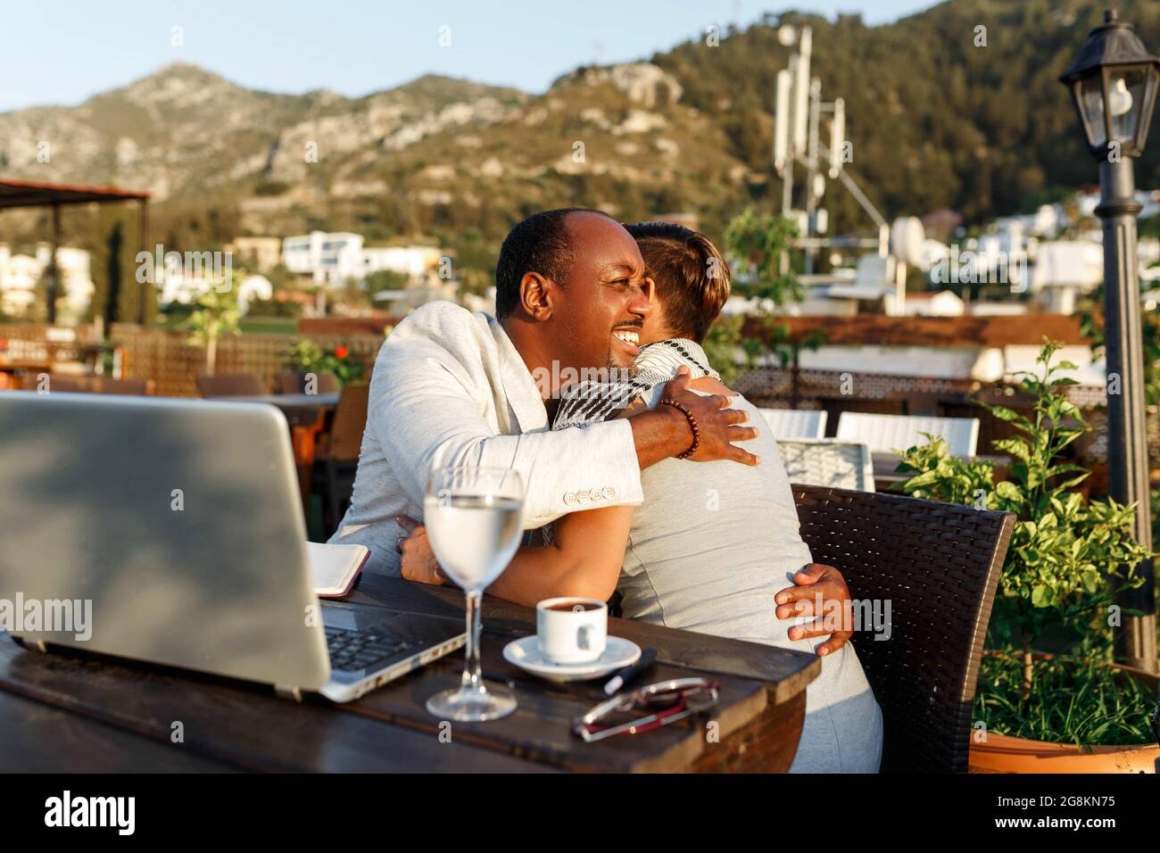 Coworking e freelance concetto, successo hugs .gara mista, metà età nero pelle uomo e donna che lavorano insieme su computer portatile mentre si siede su ca Foto Stock