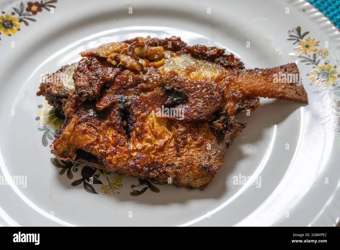 Un pesce fritto di pomodoro servito su un piatto decorato bianco, speziato cibo indiano. I Pomfrets sono pesci perciformi appartenenti alla famiglia Bramidae. Foto Stock