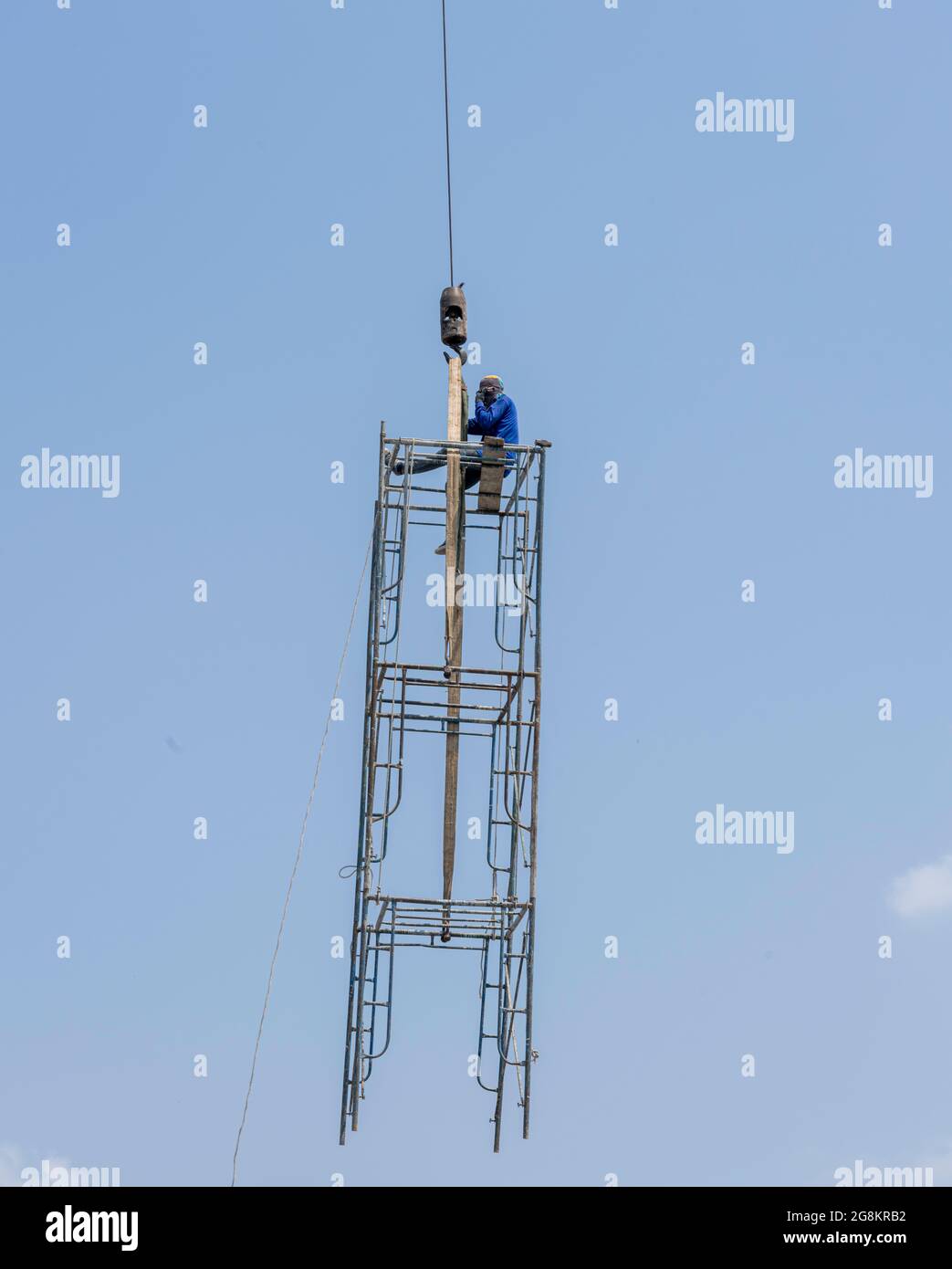 Gru mobile che solleva un uomo seduto sulla struttura temporanea in aria Foto Stock