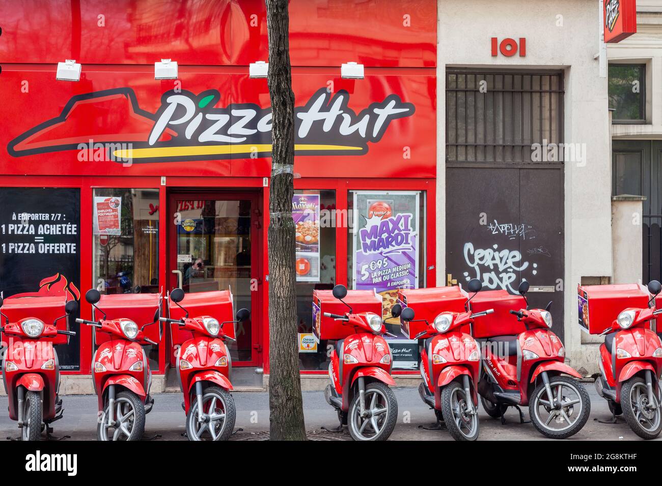 Fila di ciclomotori rossi di fronte ad un negozio di pizza. Parigi Foto Stock