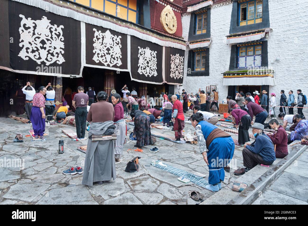 Pellegrini che pregano adorando di fronte al tempio Jokhang. Il tempio buddista in Piazza Barkhor è il tempio più sacro e importante del Tibet Foto Stock