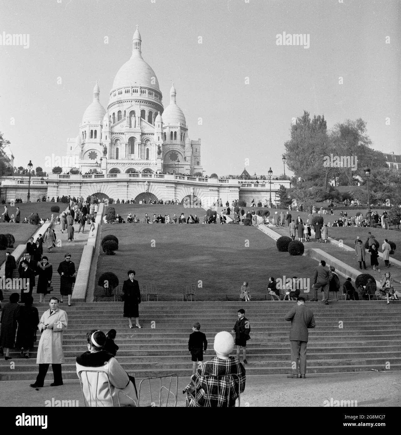 Anni '50, storica, due Signore parigine in cappotti e cappelli seduti su  sedie a terra sotto i gradini che conducono al famoso punto di riferimento  francese, la chiesa cattolica romana a cupola,