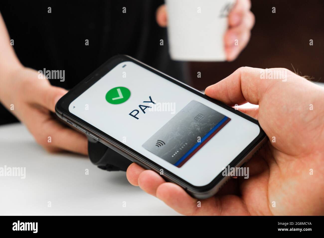 Primo piano mano uomo senza contatto pagare per il caffè da smartphone. Foto Stock