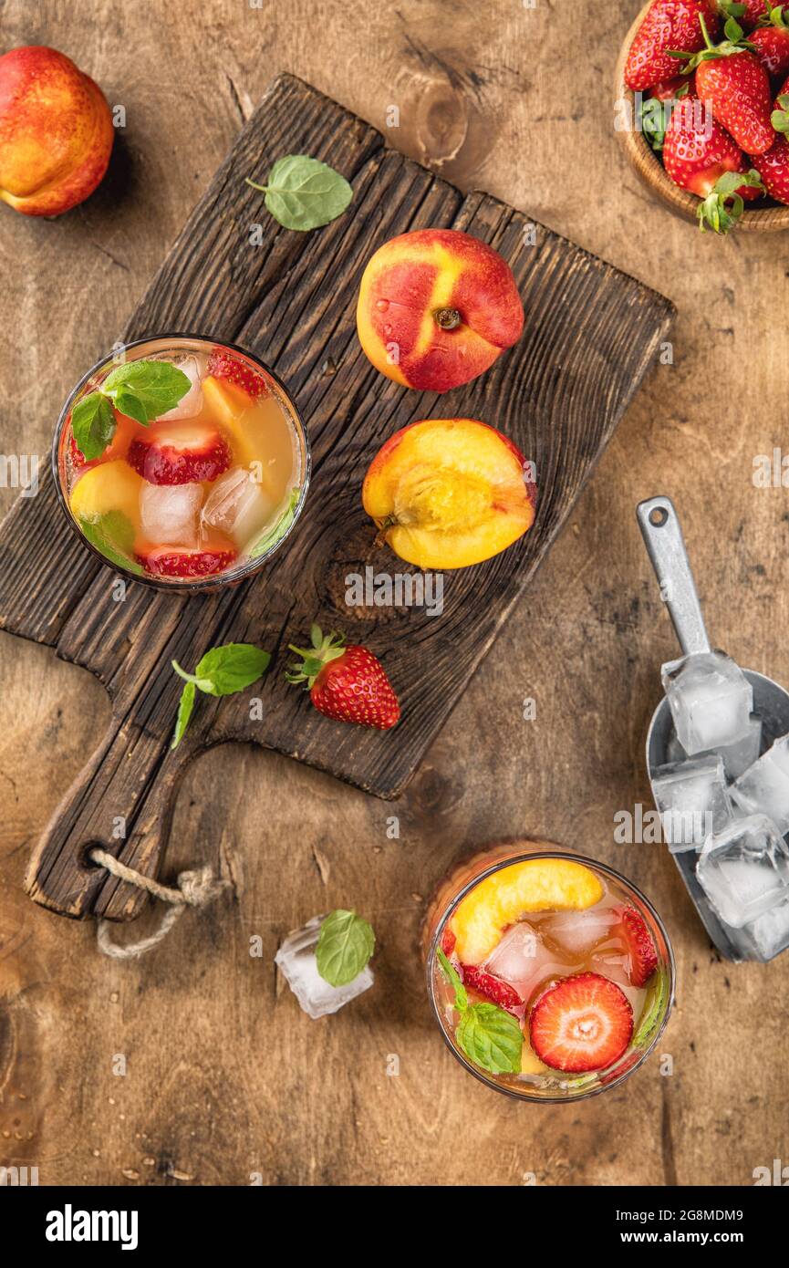 Vista dall'alto della limonata estiva. Bevanda fredda con pesca, fragola, ghiaccio, foglie di menta Foto Stock
