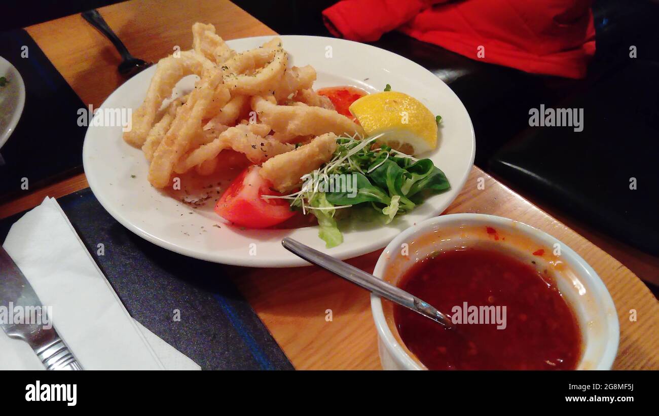 Anelli di calamari con insalata e salsa calda Foto Stock