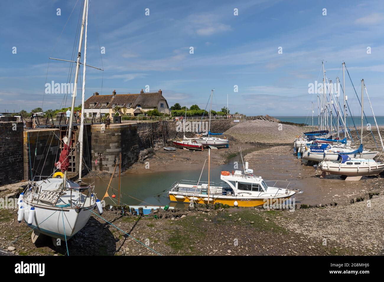 Marea fuori al porto di Porlock Weir con barche ormeggiate e cottage tradizionali sullo sfondo, Porlock, West Somerset, Inghilterra, Regno Unito Foto Stock