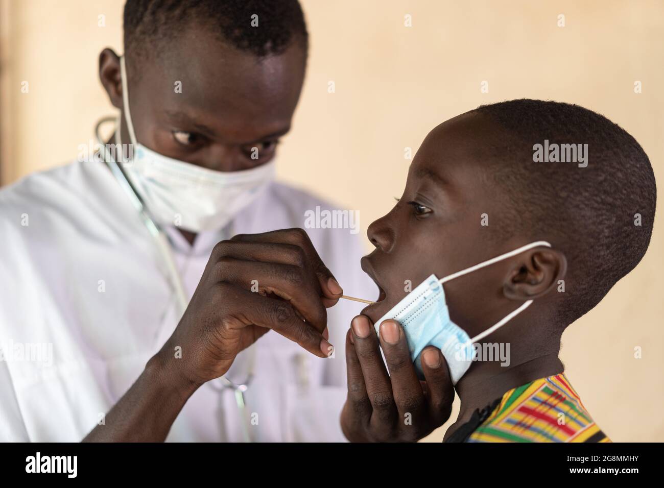 Medico nero africano con maschera viso prova ragazzo africano con cotone bastoncino test. Concetto di salute in un villaggio rurale appena fuori Bamako, Mali. Foto Stock