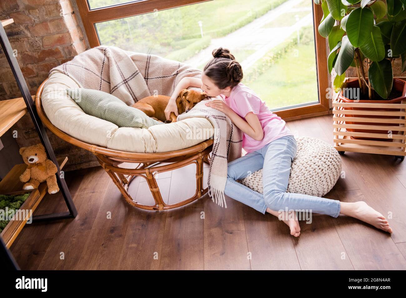 Ritratto di attraente ragazza attenta seduta sul pavimento abbracciando puppy sonnolento che riposa in casa appartamento all'interno Foto Stock