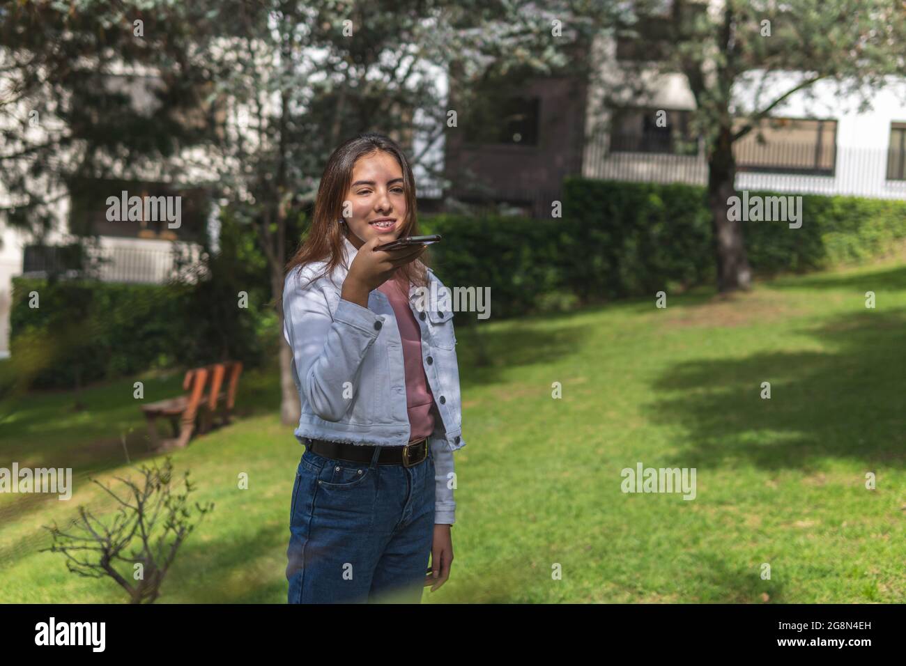 Latina teen girl inviando un messaggio audio all'aperto Foto Stock