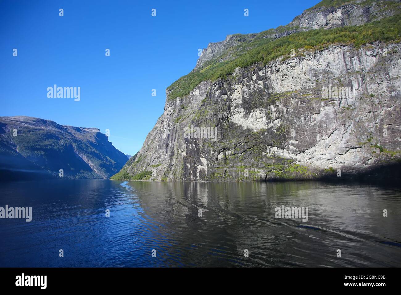 Crociera lungo il fiordo di Geiranger. Bellissimo paesaggio con riflessi delle montagne in acqua in una tranquilla giornata estiva, fiordi norvegesi, Norvegia. Foto Stock