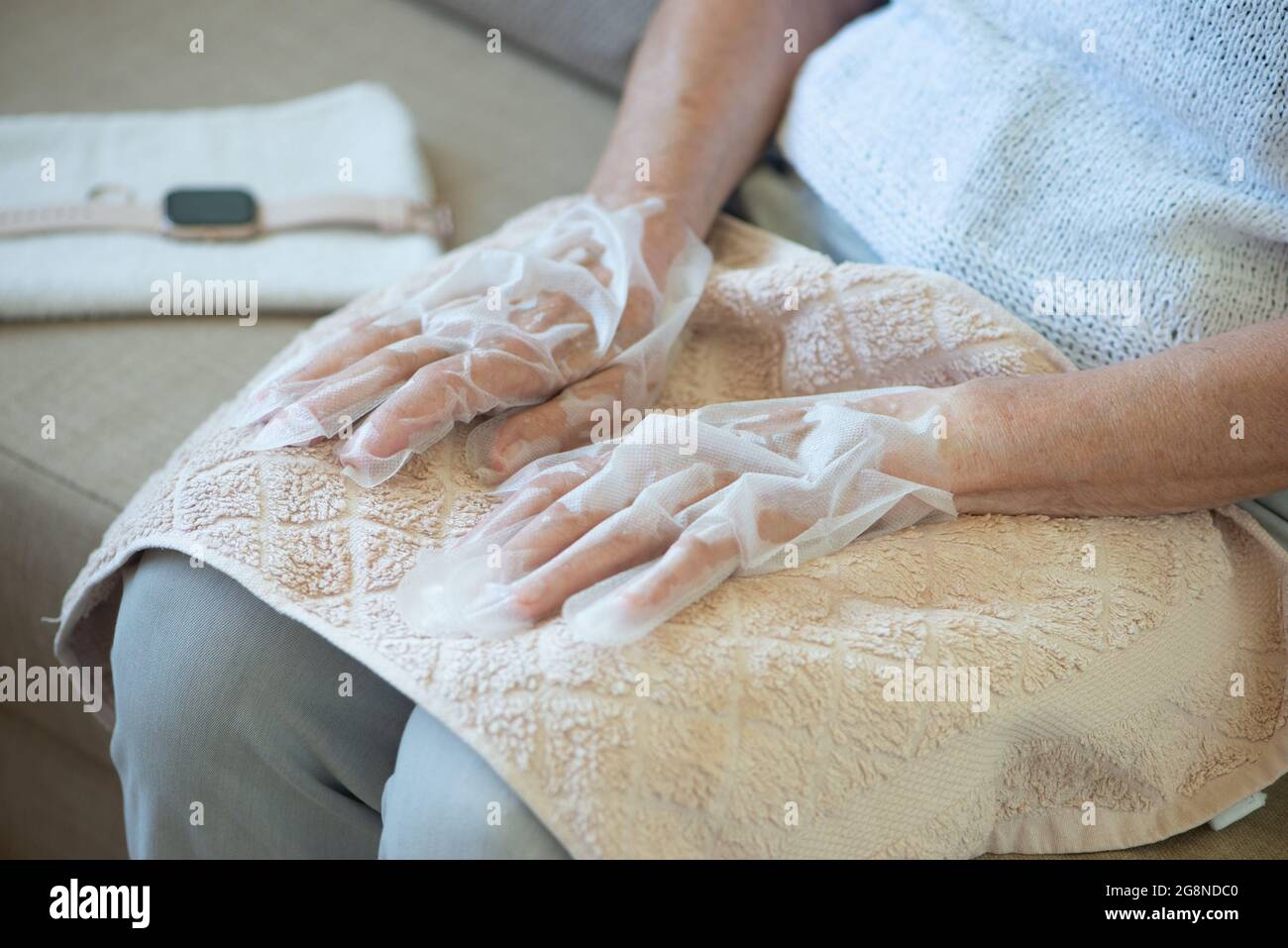 Donna anziana che indossa guanti da maschera. Guanti idratanti per  ammorbidire e proteggere la pelle delle mani. Le mani si avvicinano Foto  stock - Alamy