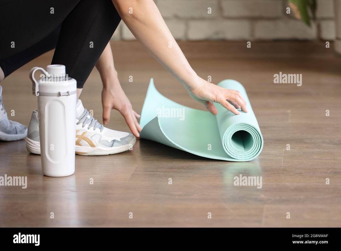 Insegnante di yoga che prepara il tappetino blu per il fitness per esercitarsi in palestra Foto Stock