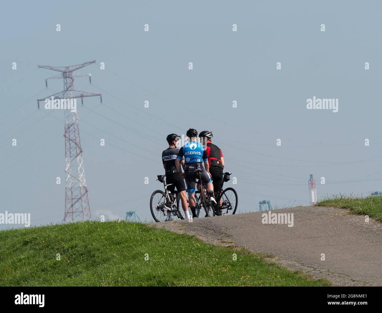 Doel, Belgio, 21 luglio 2021, tre ciclisti si stanno parlando sulla cima della diga sulle loro biciclette Foto Stock