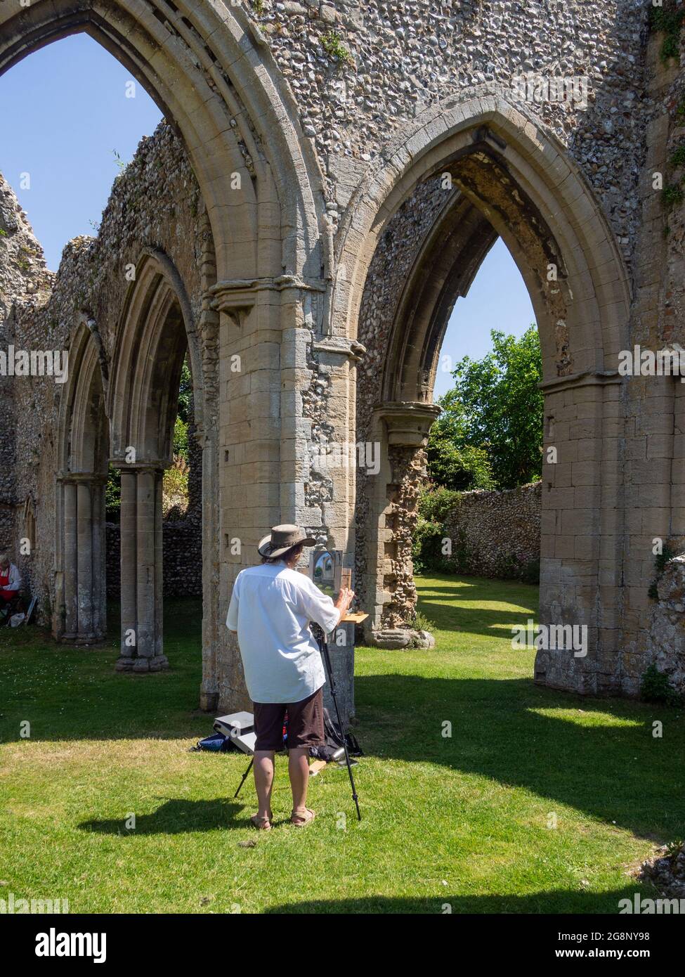 Creake Abbey, le rovine di un'abbazia agostiniana risalente al 1206, North Creake, Norfolk, UK; artista al lavoro in primo piano Foto Stock