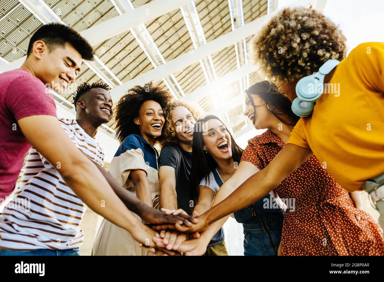 Amici multirazziali felici con le mani in pila. Gruppo multietnico di studenti universitari che si uniscono alle loro mani. Foto Stock