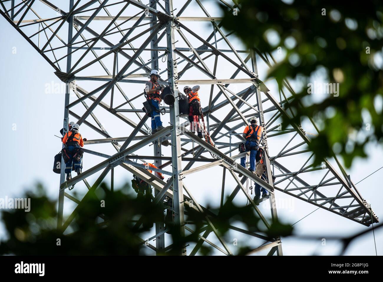 Auf einem Feld zwischen Kaarst und Düsseldorf bauen Mitarbeiter der Firma SPIE Leitungsbau einen Elektrizitätsmast auf. Wie Playmobil-Männchen sehen d Foto Stock