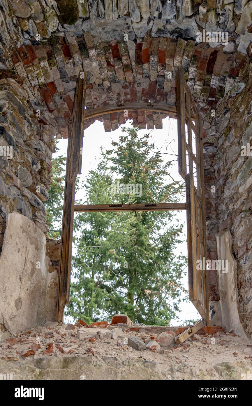 Vista attraverso una finestra danneggiata in una rovina abbandonata nel  bosco Foto stock - Alamy