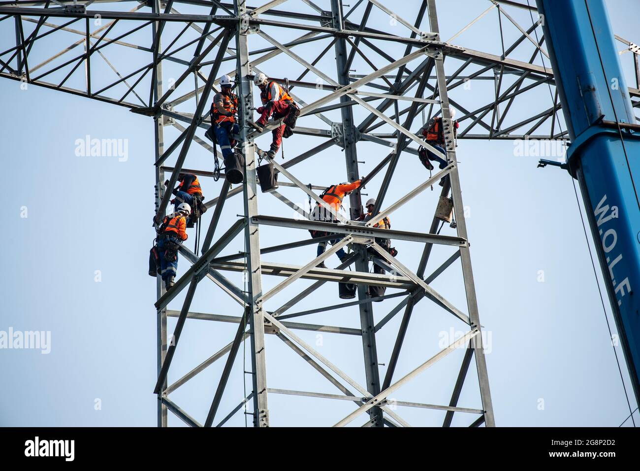 Auf einem Feld zwischen Kaarst und Düsseldorf bauen Mitarbeiter der Firma SPIE Leitungsbau einen Elektrizitätsmast auf. Wie Playmobil-Männchen sehen d Foto Stock