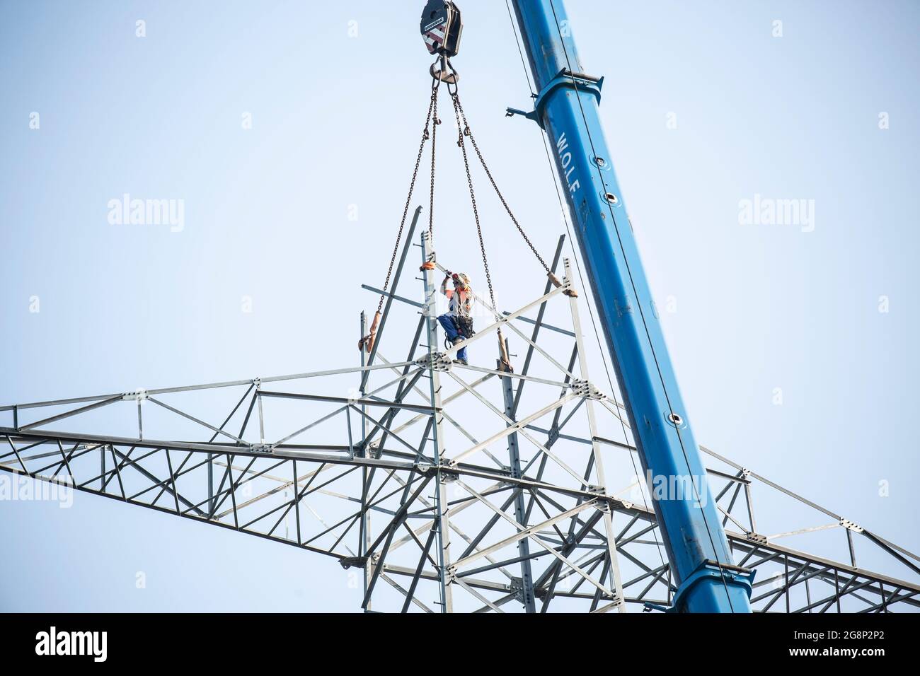 Auf einem Feld zwischen Kaarst und Düsseldorf bauen Mitarbeiter der Firma SPIE Leitungsbau einen Elektrizitätsmast auf. Wie Playmobil-Männchen sehen d Foto Stock