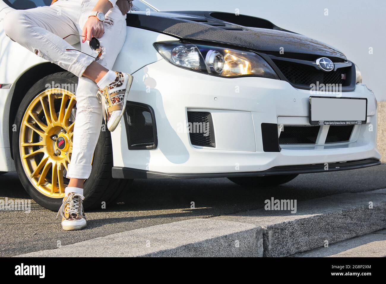 Kiev, Ucraina - 25 Marzo 2015: Subaru Impreza WRX STI. Ragazza in sneaker colorate e pantaloni bianchi. Ragazza su fondo auto. Auto e ragazza Foto Stock