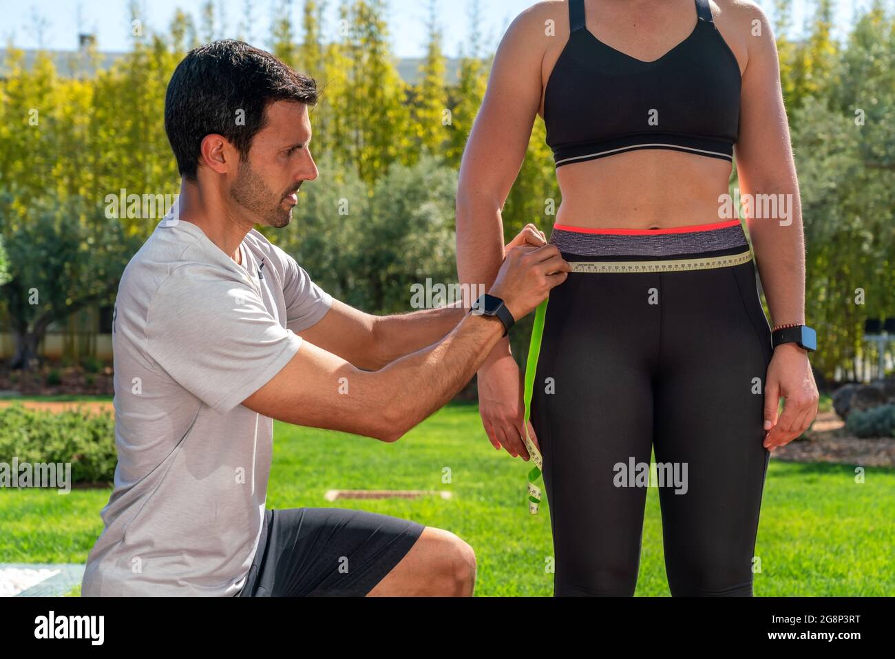 Un addestratore di idoneità misura la vita di un cliente su un programma di perdita di peso, sulla dieta e sull'addestramento. Risolvere il problema dell'obesità. Foto Stock