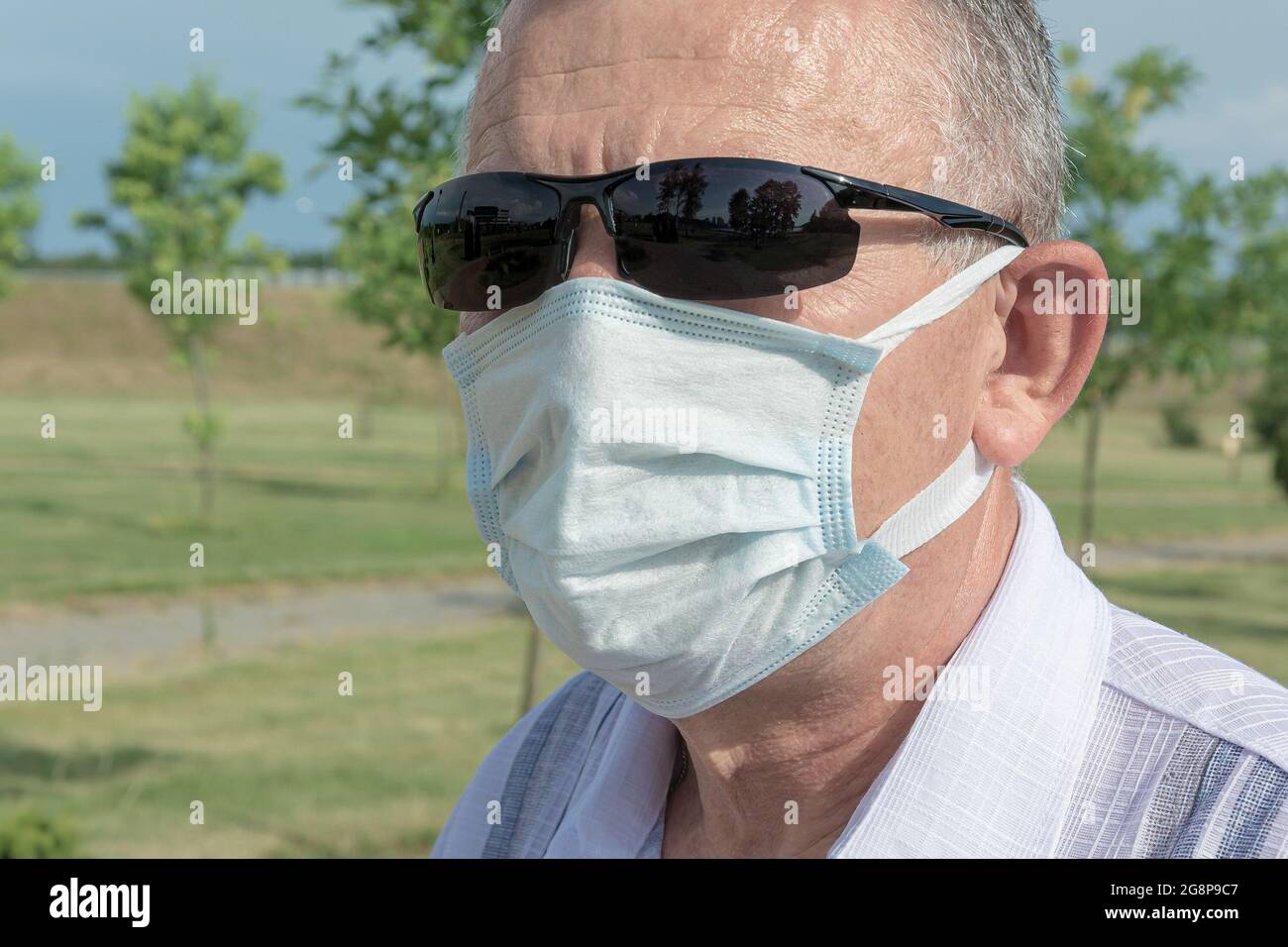 uomo che indossa occhiali da sole e una maschera medica. Primo piano, sfondo sfocato. Foto stock Foto Stock