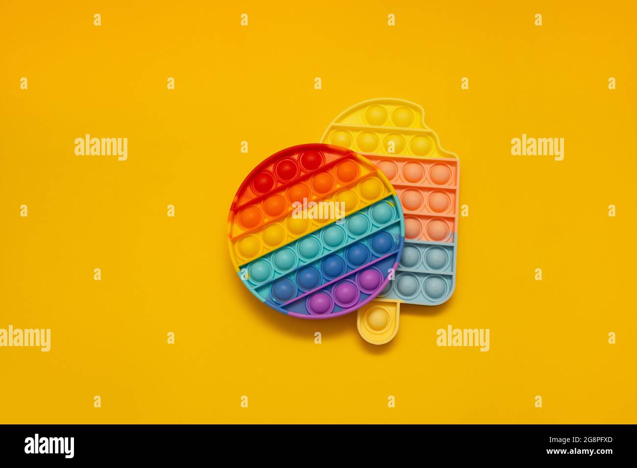 Colorati fidget anti-stress push pop IT sensoriali giocattoli su sfondo giallo. Foto Stock