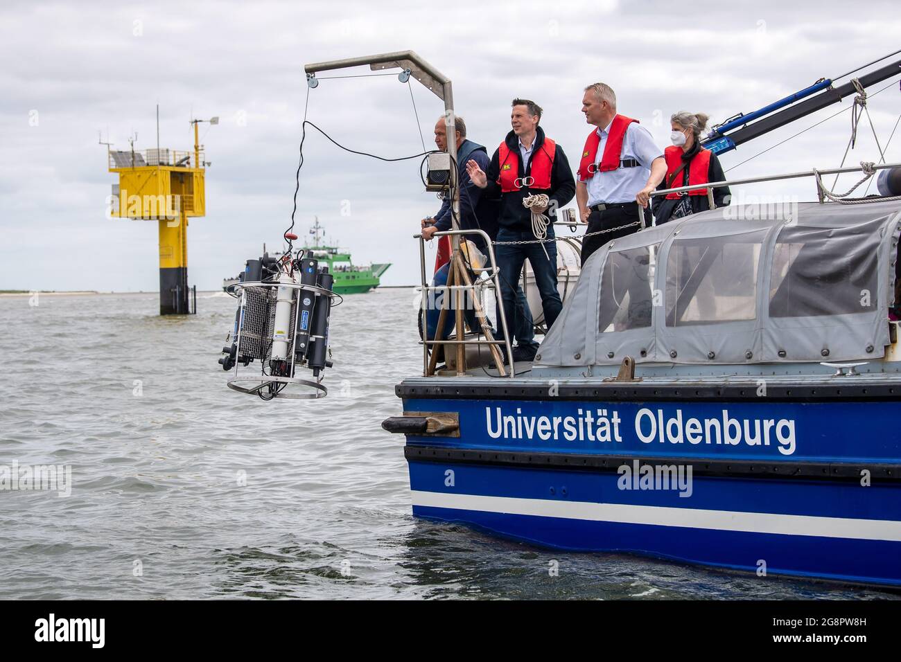 Nordsee, Germania. 22 luglio 2021. Björn Thümler,(CDU, r), ministro della scienza della bassa Sassonia, salta a bordo della nave di ricerca Otzum, che naviga tra Neuharlingersiel e Spiekeroog, e fa cadere un dispositivo di misurazione CTD nell'acqua. Thümler sta visitando la rete di ricerca costiera. Il progetto mira a studiare come la protezione costiera e la protezione degli ecosistemi possano essere riconciliate e funzionare anche a lungo termine. A tal fine, i ricercatori utilizzano i cosiddetti laboratori reali. Credit: Sina Schuldt/dpa/Alamy Live News Foto Stock