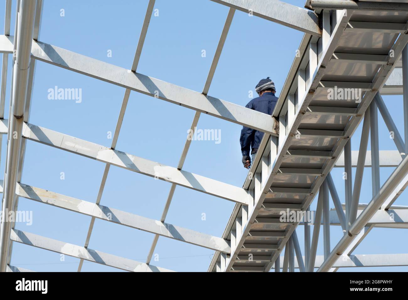 Un uomo che cammina sulle truss di acciaio leggero e la costruzione di telaio. Foto Stock