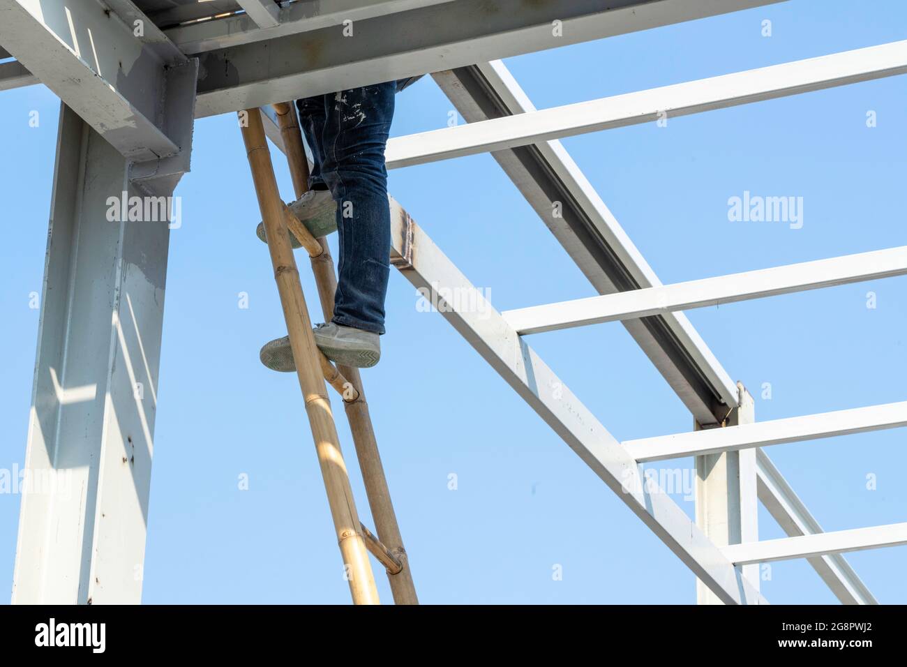 Un uomo che sale su una scala di legno. Foto Stock