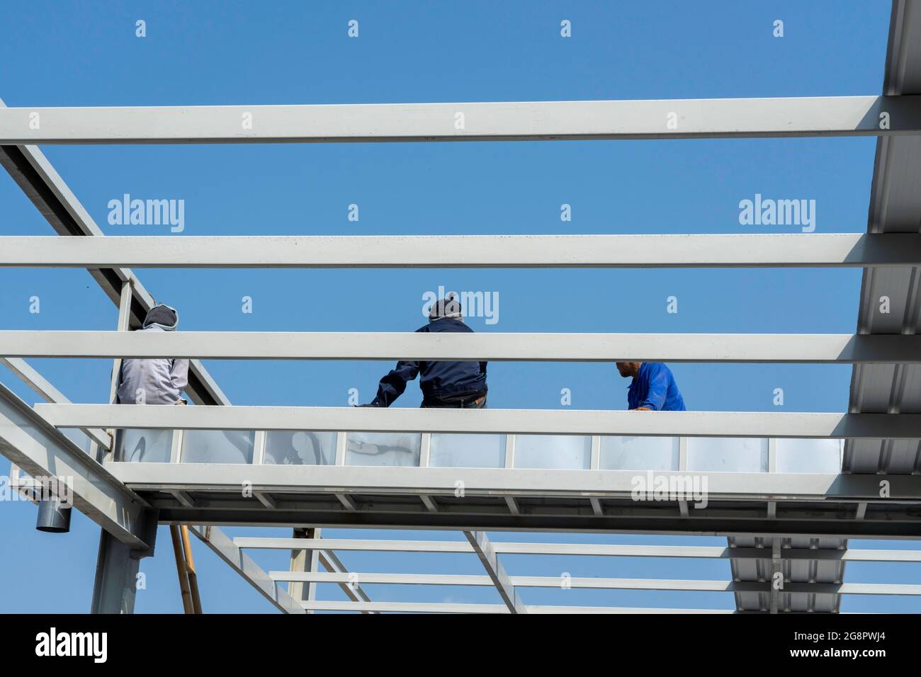 Tre uomini seduti e consultati sul tetto, Truss in acciaio leggero e costruzione di telai. Foto Stock
