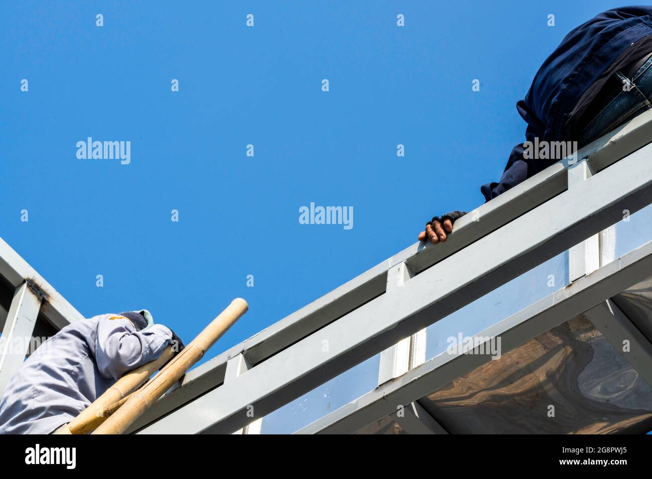 Due persone che si siedono e si consultano sul tetto con Truss in acciaio leggero e struttura a telaio. Foto Stock