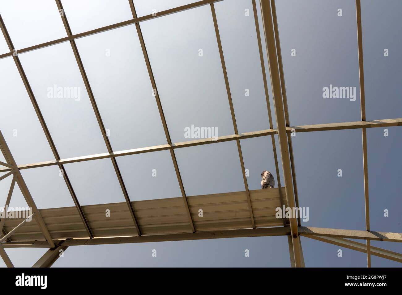 Un uomo che cammina sul tetto in metallo con truss in acciaio leggero e struttura a telaio. Foto Stock