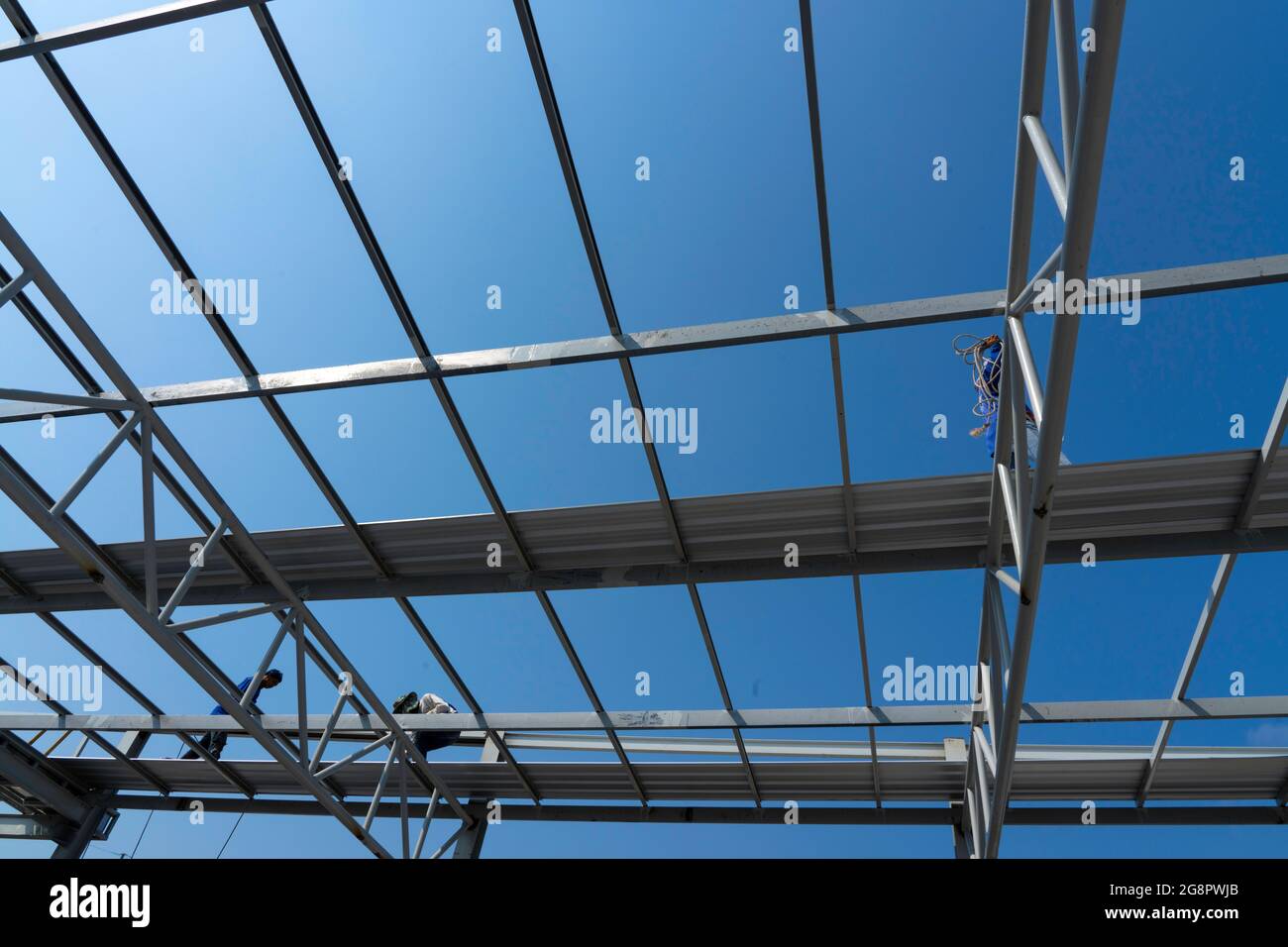 Tre uomini stanno installando la lamiera del tetto su truss di acciaio leggero e costruzione del telaio. Foto Stock