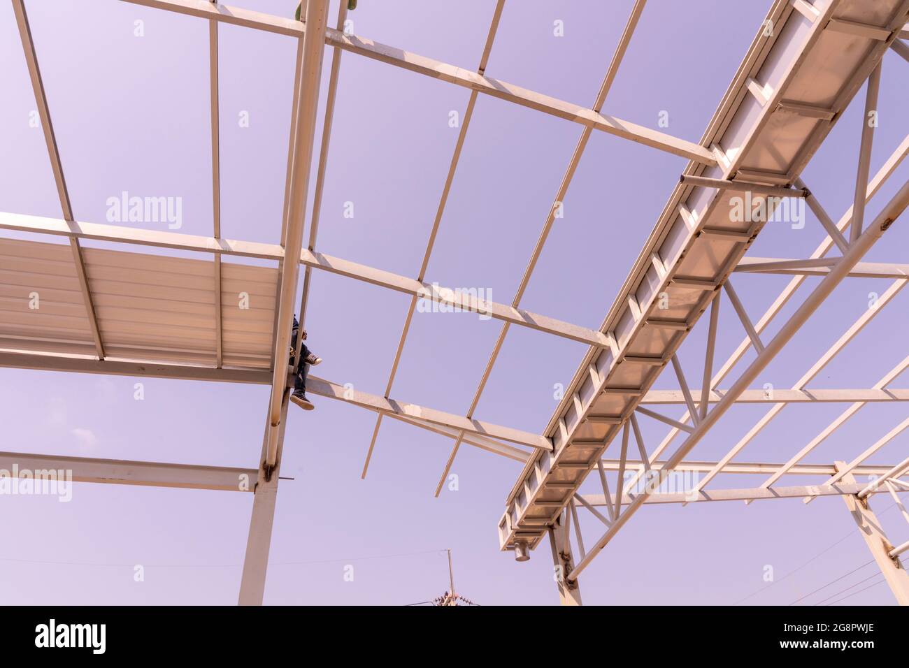 Lavoratore di costruzione seduto sulle truss di acciaio leggero e costruzione di telaio. Foto Stock